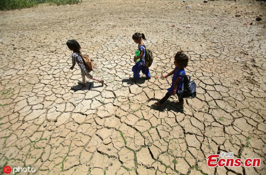 Indian school children walk on the dried pond after attends school on a hot summer day outskirts of Jammu, India, Thursday, May.30,2019.(Photo/IC)