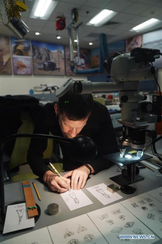 A staff member draws pictures of small fossils in the new dinosaur and fossil hall of the Smithsonian\'s National Museum of Natural History in Washington D.C., the United States, on June 4, 2019. The Smithsonian\'s National Museum of Natural History will reopen its dinosaur and fossil hall \