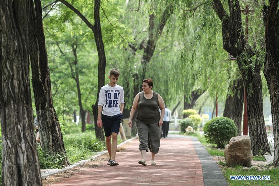 A Russian patient (R) walks with her son at Tanggangzi Hospital in Anshan, northeast China\'s Liaoning Province, June 4, 2019. Featured with traditional Chinese medicine therapy, Tanggangzi Hospital has attracted many Russian patients who come here to receive rehabilitation treatments, such as acupuncture, physiotherapy, cephalic magnet therapy. The hospital received more than 6,000 Russian patients in one year at the peak. (Xinhua/Pan Yulong)
