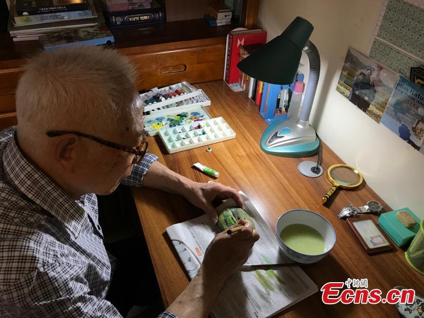 Zhang Yulin gives a final touch on his painting on a stone. Zhang, 81, from southwest China’s Chongqing municipality, collects stones from the Yangtze River banks and turns them into artworks with paintings.  (Photo: China News Service/Xiao Jiangchuan)