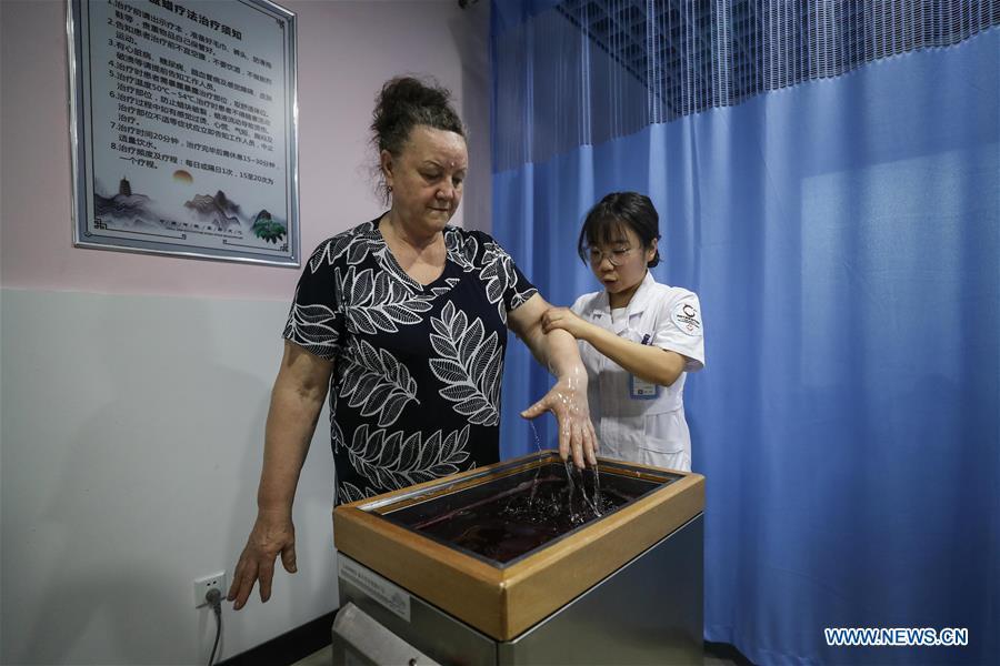 A Russian patient receives wax therapy at Tanggangzi Hospital in Anshan, northeast China\'s Liaoning Province, June 4, 2019. Featured with traditional Chinese medicine therapy, Tanggangzi Hospital has attracted many Russian patients who come here to receive rehabilitation treatments, such as acupuncture, physiotherapy, cephalic magnet therapy. The hospital received more than 6,000 Russian patients in one year at the peak. (Xinhua/Pan Yulong)