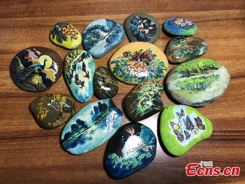 Zhang Yulin shows his paintings on stones.Zhang, 81, from southwest China’s Chongqing municipality, collects stones from the Yangtze River banks and turns them into artworks with paintings.  (Photo: China News Service/Xiao Jiangchuan)