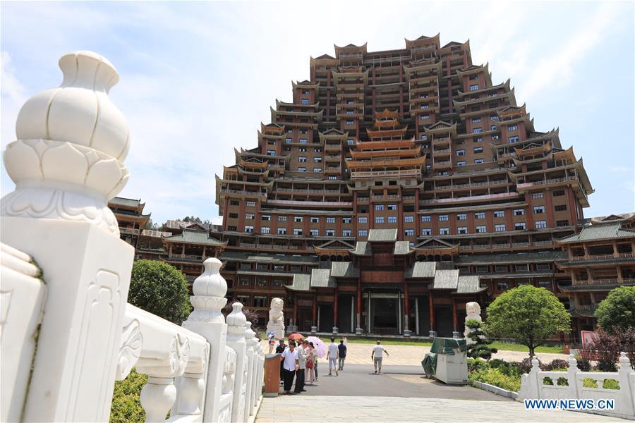 Tourists visit a wooden building of Shui ethnic group in Yingshan Town of Dushan County, southwest China\'s Guizhou Province, June 7, 2019. The 24-story, 99.9-meter-high traditional Shui-style wooden building in Dushan is of \