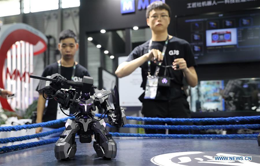 A staff member (R) demonstrates a fighting robot during the 2019 Consumer Electronics Show (CES) Asia in east China\'s Shanghai, June 11, 2019. The 2019 Consumer Electronics Show (CES) Asia kicked off on Tuesday in Shanghai. The three-day exhibition showcased the latest achievements in 5G technology, artificial intelligence, augmented/virtual reality and vehicle technology. (Xinhua/Fang Zhe)