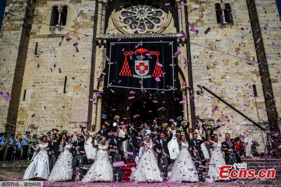 Brides and grooms pose for a photo outside the Lisbon\'s cathedral following their wedding ceremony in Lisbon on June 12, 2019. It is Lisbon\'s wedding of the year. Crowds gather at the cathedral, hoping to catch a glimpse of the newlyweds as cameras lie in wait. Then not one, but 11 couples walk out, fresh from tying the knot today in an all-expenses-paid ceremony, the beneficiaries of a decades-long annual tradition that fetes the Portuguese capital\'s beloved patron Saint Anthony, matchmaker extraordinaire.(Photo/Agencies)