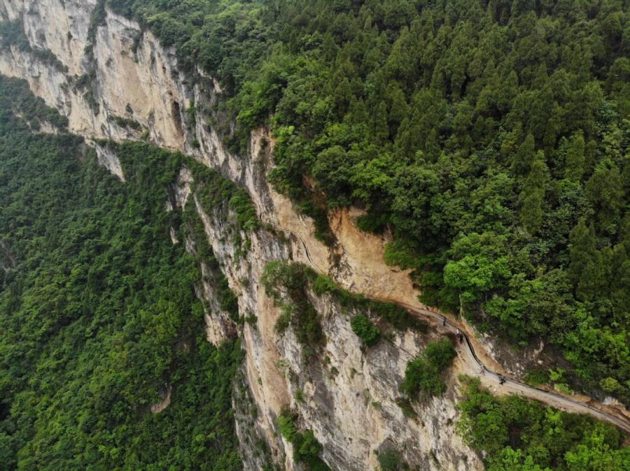 Residents walk along the canal carved into cliffs in Gaoliu village, Southwest China\'s Guizhou Province.  (Photo by Han Xianpu/For chinadaily.com.cn)