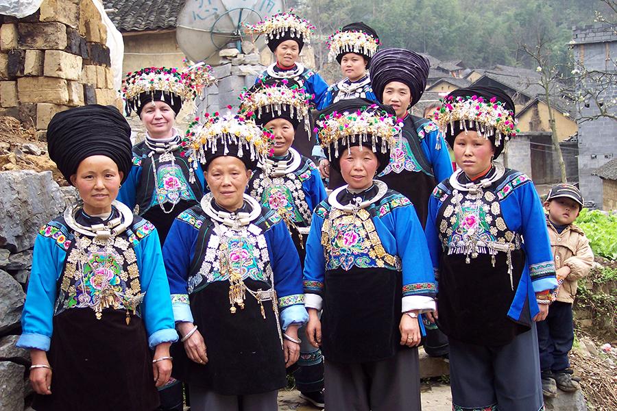 Dorothy Lacy, second row, left, and some of the craftswomen who create embroidered items for the Shenaini website pose in Miao traditional costume in 2006. (Photo provided to chinadaily.com.cn)