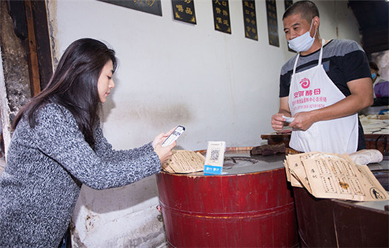 A customer buys sesame seed cakes via smartphone in Wuzhen, Zhejiang province. (Photo/China Daily) A customer buys sesame seed cakes via smartphone in Wuzhen, Zhejiang province. (Photo/China Daily)