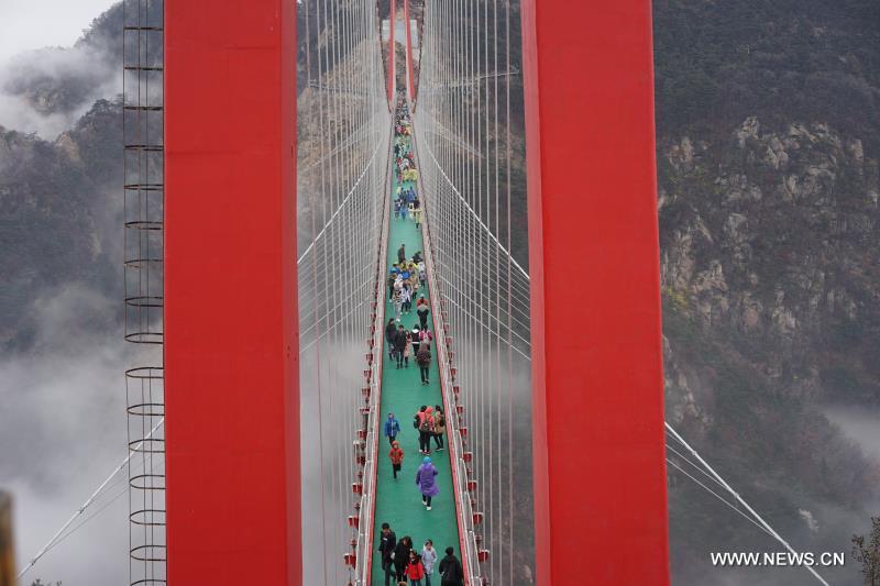 Tourists walk on pedestrian suspension bridge in E China
